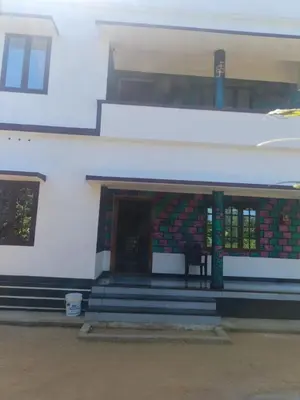 a white building with stairs and a door with a window at Sandal Homestay in Marayoor