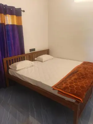 a bedroom with a bed with a blanket on it at Sandal Homestay in Marayoor