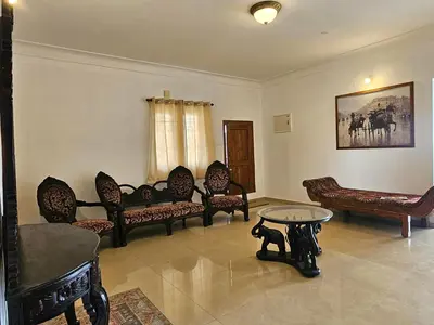 a living room with chairs and a table and a couch at Hestia chalet 3BHK near Ooty lake in Ooty
