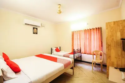 a bedroom with a bed and a chair and a window at Hotel O Kingston Residency in Vānivilāsa Puram