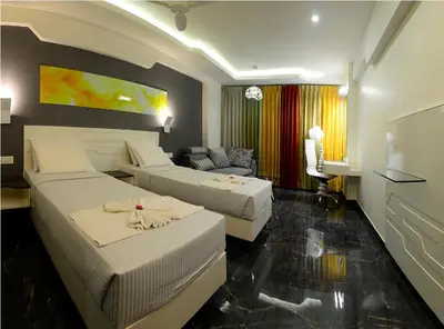 a hotel room with two beds and a couch at Hotel Vijay Elanza in Coimbatore
