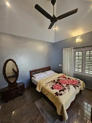 a bedroom with a bed with a ceiling fan at Serene Villa in Koroth