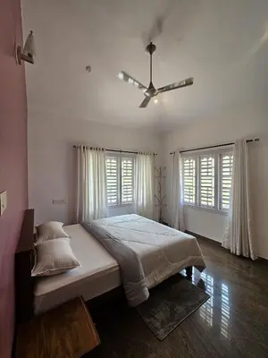 a bedroom with a large bed and a ceiling fan at Serene Villa in Koroth
