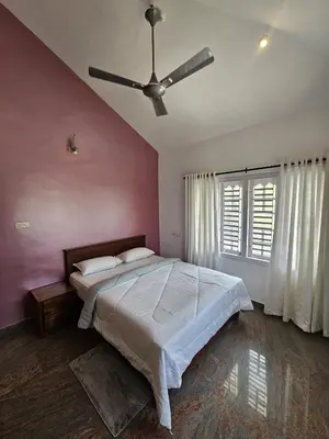 a bedroom with a large bed with a ceiling fan at Serene Villa in Koroth