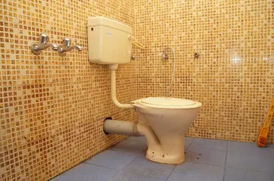 a bathroom with a toilet in a tiled wall at The Marayoor in Marayoor