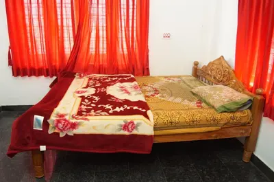 a bed in a room with red curtains at The Marayoor in Marayoor