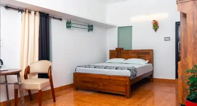a bedroom with a bed and a chair and a table at Nest Nature Homestay in Kalpetta
