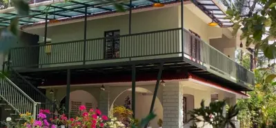 a balcony on a house with pink flowers at Nest Nature Homestay in Kalpetta