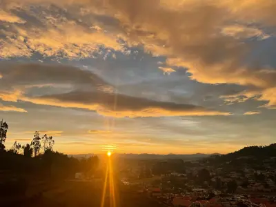 a view of the sun setting over a city at VR cottage in Ooty