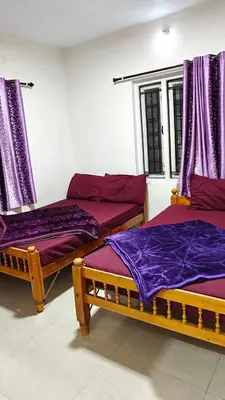 two beds in a room with purple sheets at VR cottage in Ooty