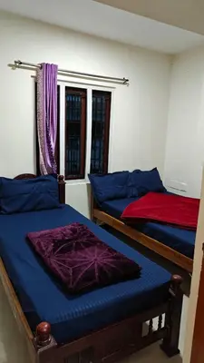 a bedroom with two beds with blue and purple sheets at VR cottage in Ooty