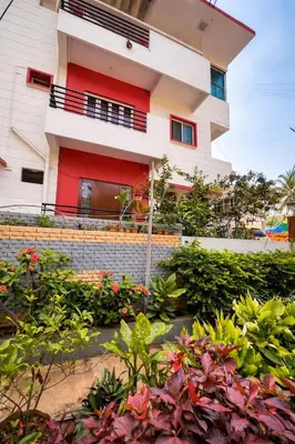 a house with red trim and flowers in front of it at Casa Mysuru Boulevard Stay Cozy 2BHK AC in Mysore