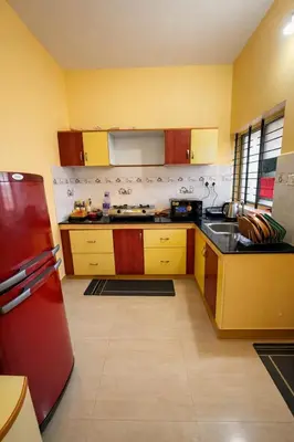 a kitchen with yellow cabinets and a red refrigerator at Casa Mysuru Boulevard Stay Cozy 2BHK AC in Mysore