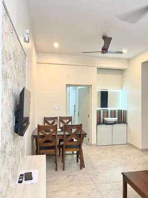 a living room with a table and chairs and a kitchen at Serenity Homes near Rajagiri Hospital in Alwaye