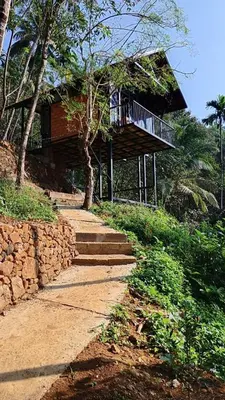 a building with a balcony and stairs in front of it at Waterfall View Stay Chappanthotam Kozhikode in Kuttyādi