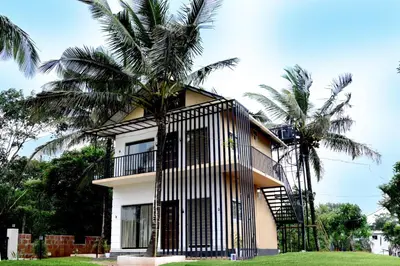 a building with a palm tree in front of it at Shade trees in Padinjarathara
