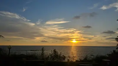 a sunset over the ocean with the sun setting at Razena Beach in Green Island