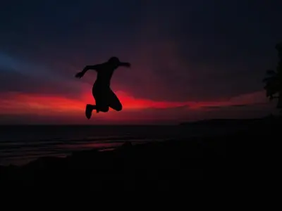a person jumping in the air on the beach at sunset at Razena Beach in Green Island