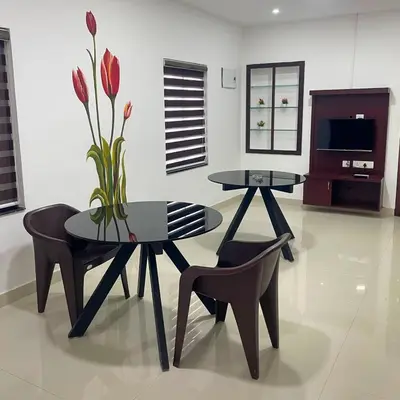 a dining room with two tables and a vase with flowers at Edakkal Pool Villa in Ambalavayal