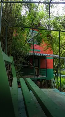 a building with a green bench in front of it at Bamboo Planet Resort in Vythiri