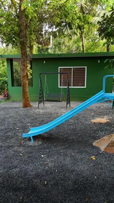 a blue slide in a park with a green building at Bamboo Planet Resort in Vythiri