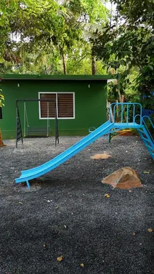 a blue slide in front of a green building at Bamboo Planet Resort in Vythiri