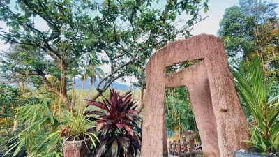 a large stone sign in front of trees at Pepper Valley Resort in Kalpetta