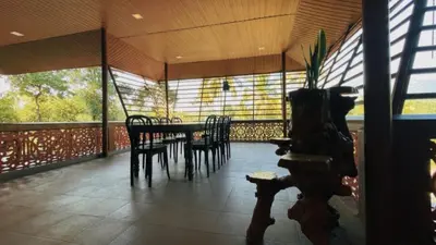 a dining room with a table and chairs on a porch at Pepper Valley Resort in Kalpetta