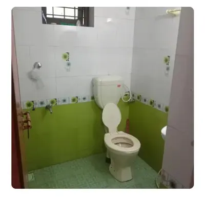 a green and white bathroom with a toilet and a sink at Dream Home in Irimbranallūr