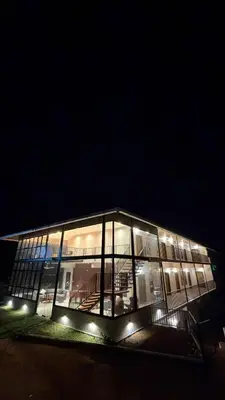 a large glass building with lights in the dark at Coorg Homes in Madikeri