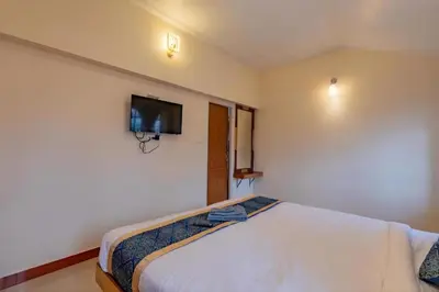 a bedroom with a bed with a tv on the wall at Pentoz Hotels Boutique Stay Near Botanical Garden Ooty in Ooty