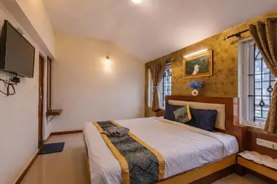 a bedroom with a bed and a flat screen tv at Pentoz Hotels Boutique Stay Near Botanical Garden Ooty in Ooty