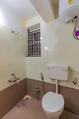 a bathroom with a toilet and a sink and a window at Pentoz Hotels Boutique Stay Near Botanical Garden Ooty in Ooty