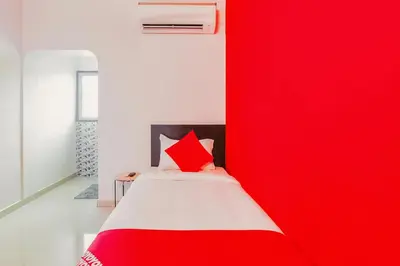 a bedroom with a red wall next to a bed at Super Hotel O By OYO Maruthi Gandhi Park in Coimbatore
