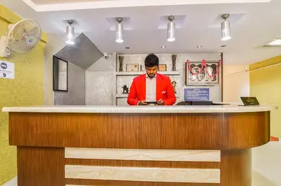 a man standing at a counter with a tablet at Super Hotel O By OYO Maruthi Gandhi Park in Coimbatore