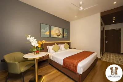 a bedroom with a bed and a table and a chair at Nilayat Inn in Ollur