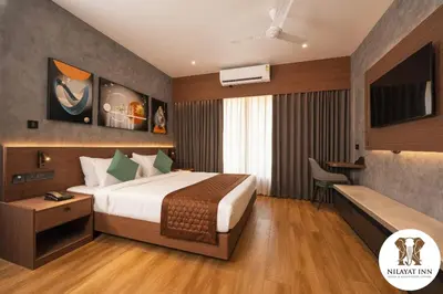 a hotel room with a bed and a desk at Nilayat Inn in Ollur