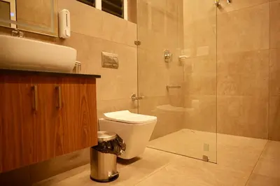 a bathroom with a toilet and a glass shower at Manayath Wayanad Premium Pool Resort in Wayanad