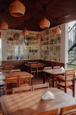 a restaurant with wooden tables and chairs and bottles on the wall at Manayath Wayanad Premium Pool Resort in Wayanad