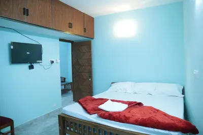 a bedroom with a bed with a red blanket and a tv at Thulir Homestay Valparai in Vālpārai