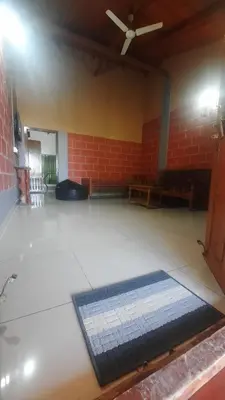 an empty room with a ceiling fan and a brick wall at Roshan Homestay in Madikeri