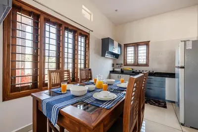 a kitchen with a wooden table with chairs and a refrigerator at White Meadows Mysore in Mysore