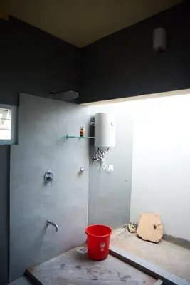 a shower with a red bucket in a bathroom at House StoneHaven in Kaniyāmbetta
