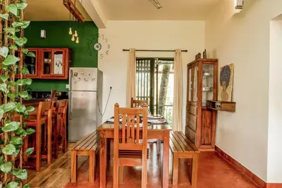 a kitchen with a table and chairs and a refrigerator at House StoneHaven in Kaniyāmbetta