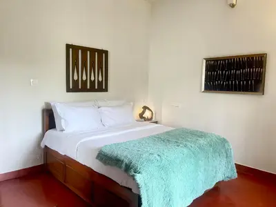 a bedroom with a bed with a green blanket on it at House StoneHaven in Kaniyāmbetta
