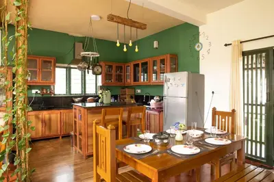 a kitchen with a wooden table and a refrigerator at House StoneHaven in Kaniyāmbetta