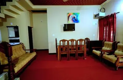 a living room with couches and a table and chairs at Hamai town villa in Ambalavayal