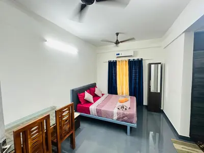a small bedroom with a bed with pink pillows at Silver Gate Rooms in Kozhikode