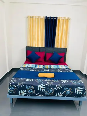 a bed with red and blue pillows in a room at Silver Gate Rooms in Kozhikode