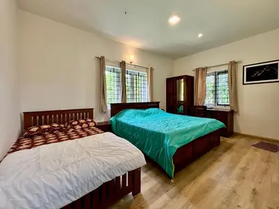 two beds in a bedroom with two windows at Easters home in Kotagiri